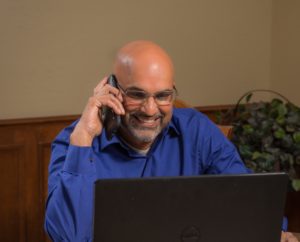 SS smiling on phone cropped and sized for web Sajjan Sharma, CrossPoint Clinical Service's Director of Marketing and Development